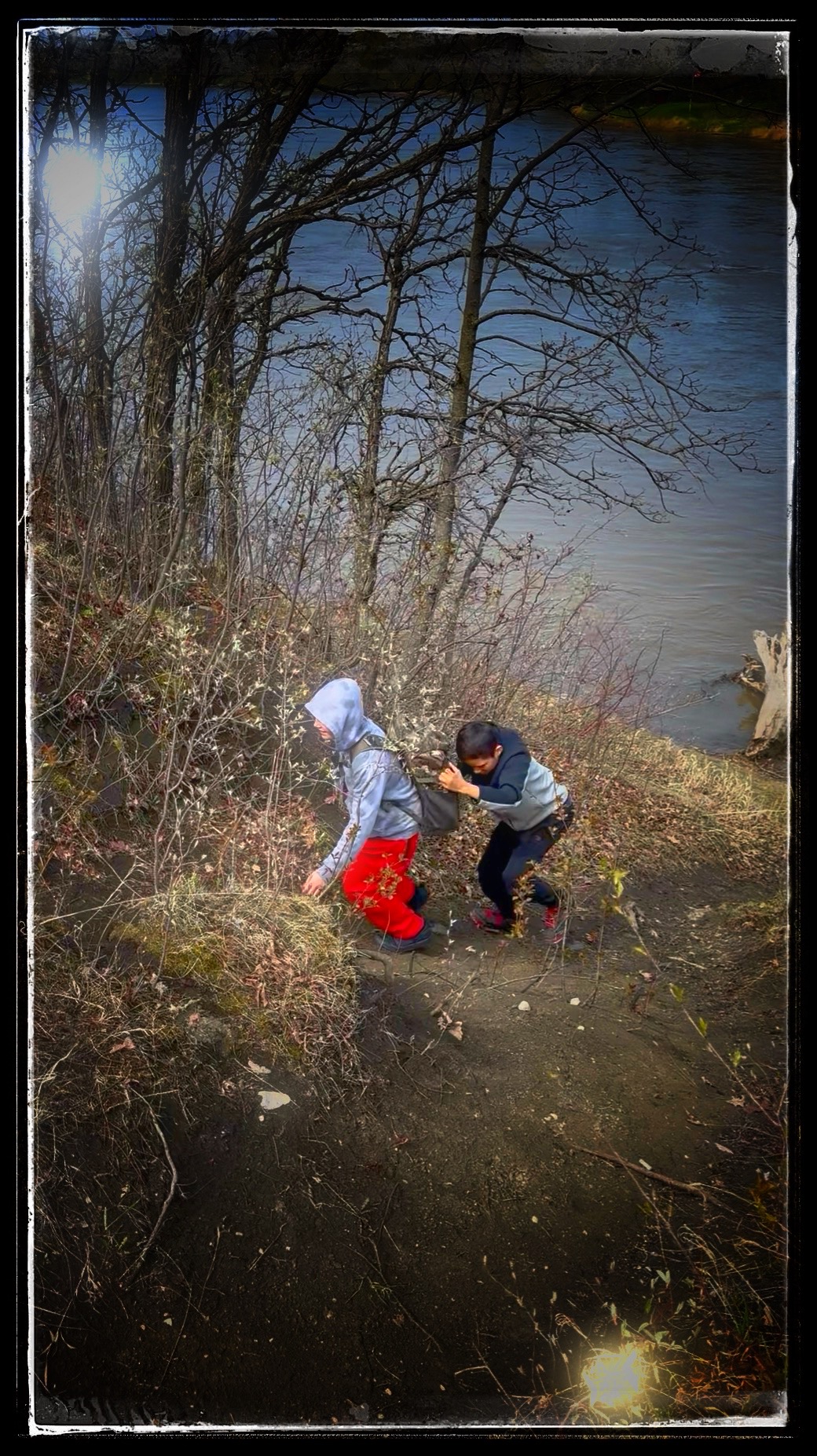 Participants helping each other climb a riverbank