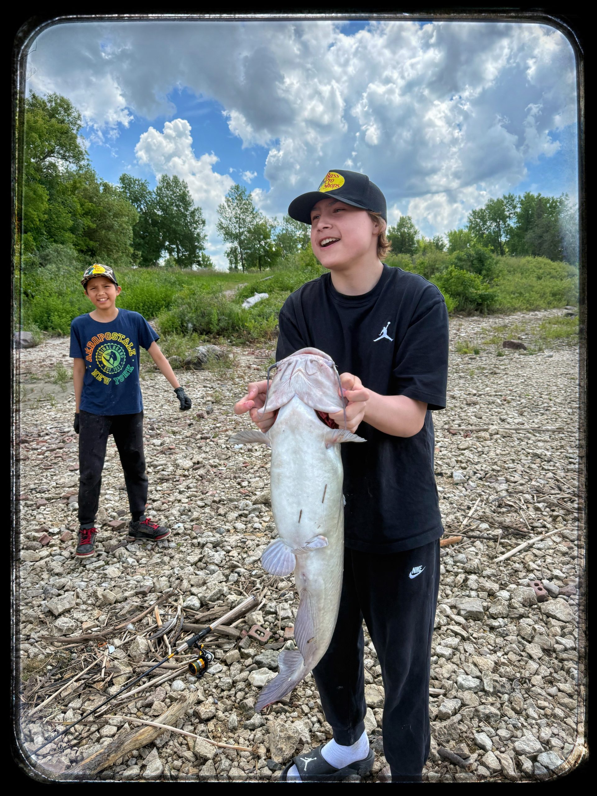 A young participant holding a fish beside the river